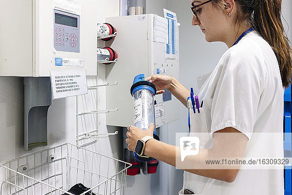 Doctor holding pneumatic tube carrier while standing in pharmacy