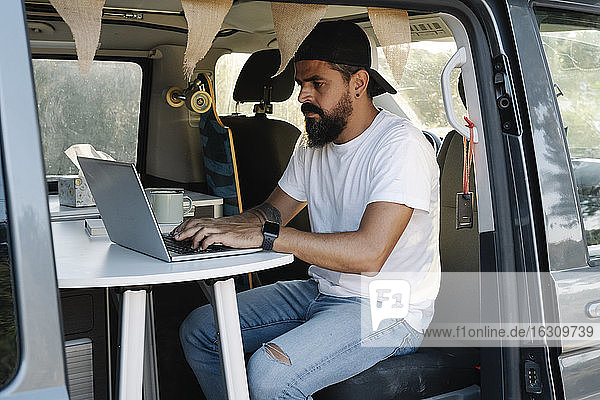Älterer Mann benutzt Laptop  während er im Van sitzt