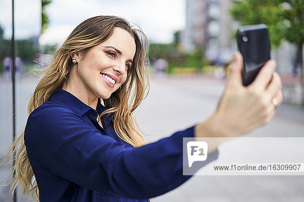 Lächelnde schöne Frau nimmt Selfie in der Stadt