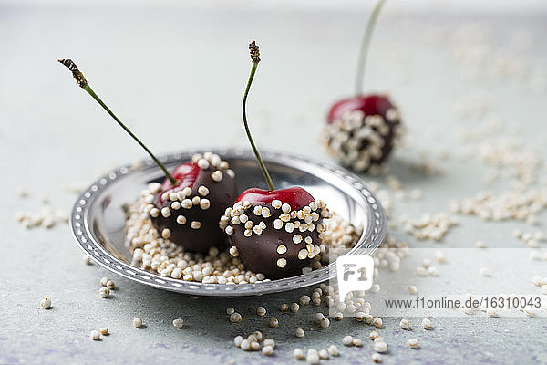 Nahaufnahme von mit Schokolade überzogenen Kirschen und Quinoa in einem Teller auf dem Tisch