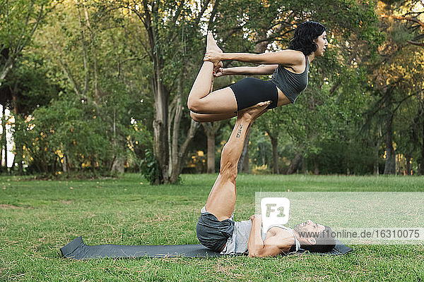 Mann balanciert Freundin auf den Beinen  während er im Park Acroyoga macht