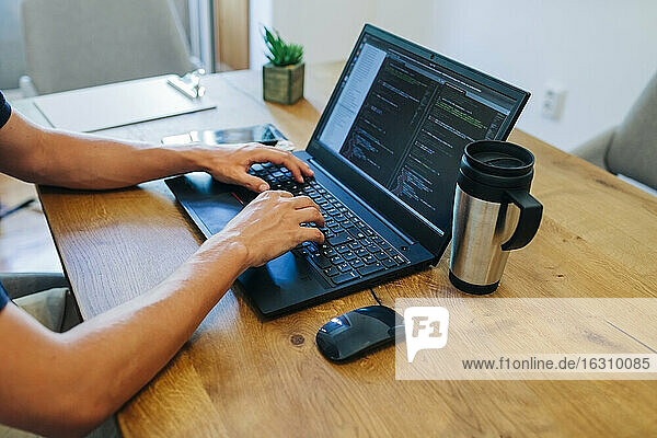 Männlicher Webdesigner beim Programmieren am Laptop am Schreibtisch im Büro