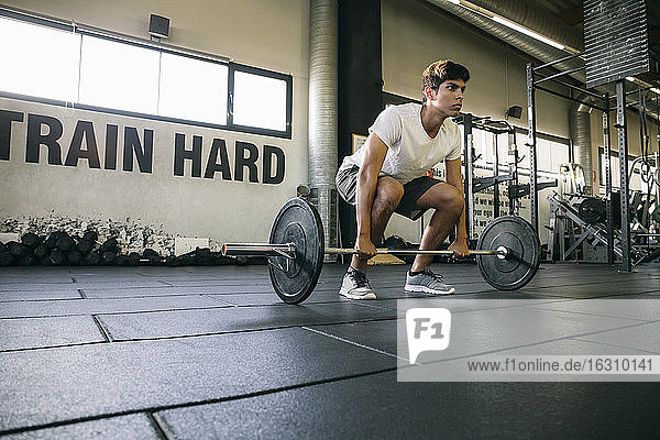 Male athlete lifting deadlift while exercising in gym