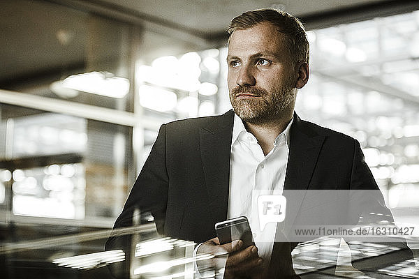 Portrait of businessman with smartphone looking sideways