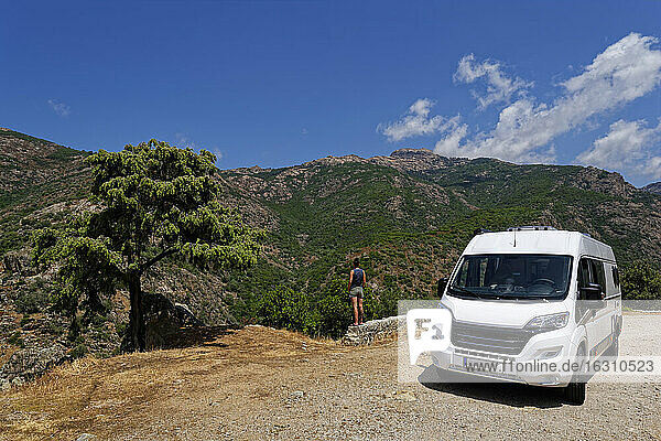 Frankreich  Corse-du-Sud  Piana  Van geparkt in Calanques de Piana mit Frau  die die umliegende Landschaft im Hintergrund bewundert