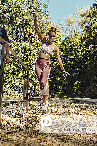 Woman balancing on rope on a fitness trail