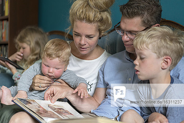 Familie schaut sich ein Fotoalbum an  während sie im Wohnzimmer sitzt
