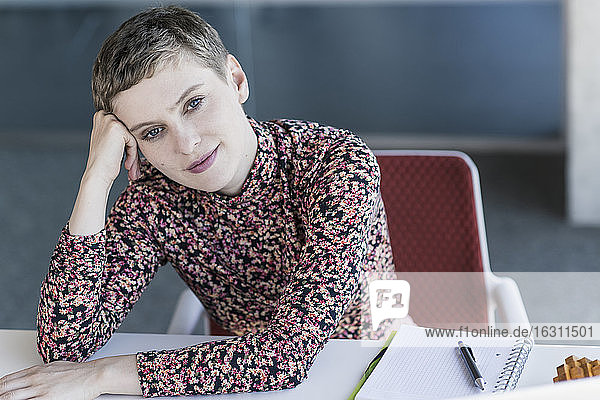 Porträt einer selbstbewussten Geschäftsfrau  die sich im Büro auf den Schreibtisch stützt