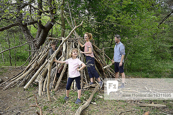 Mädchen hält einen Baumstamm  während sie mit ihrer Familie ein Lager im Wald baut