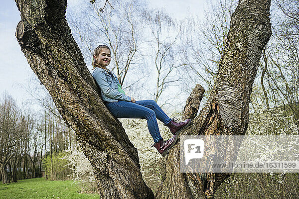 Lächelndes Mädchen balanciert über einen Baumstamm im Park
