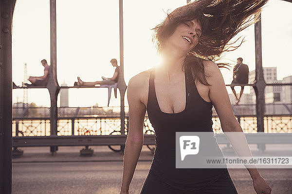 Woman tossing hair in city at sunset