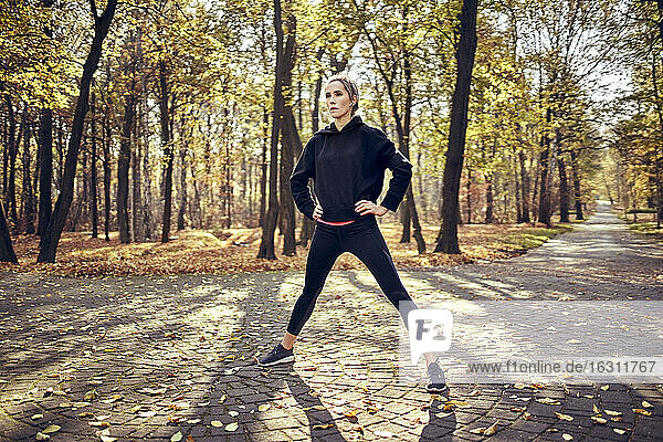 Young female jogger standing with open legs in autumn forest