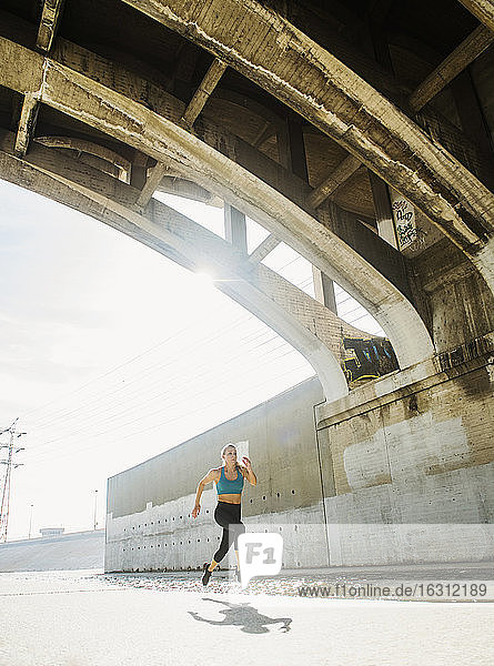 USA  California  Los Angeles  Sporty woman running underneath bridge