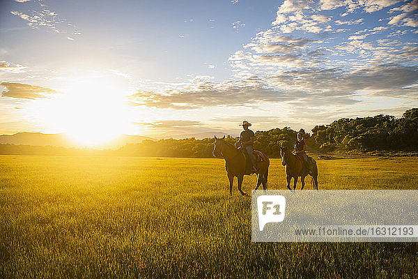 USA  Utah  Salem  Father and daughter (14-15) riding horses at sunset