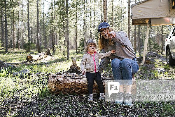 Mutter mit kleiner Tochter (2-3) sitzt auf einem Baumstamm im Uinta-Wasatch-Cache National Forest