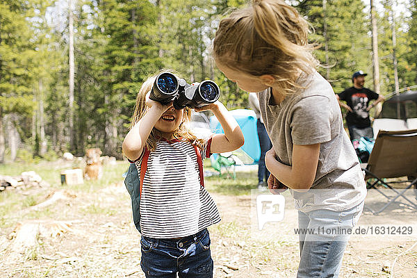 Girls (4-5  6-7) playing with binoculars on camping in forest  Wasatch-Cache National Forest