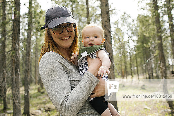 Porträt einer lächelnden Frau mit kleinem Sohn (6-11 Monate) im Wald  Wasatch-Cache National Forest