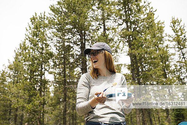 Lächelnde Frau hält Teller beim Camping im Wald  Wasatch-Cache National Forest