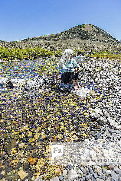 USA  Idaho  Sun Valley  Woman sitting on rock in river