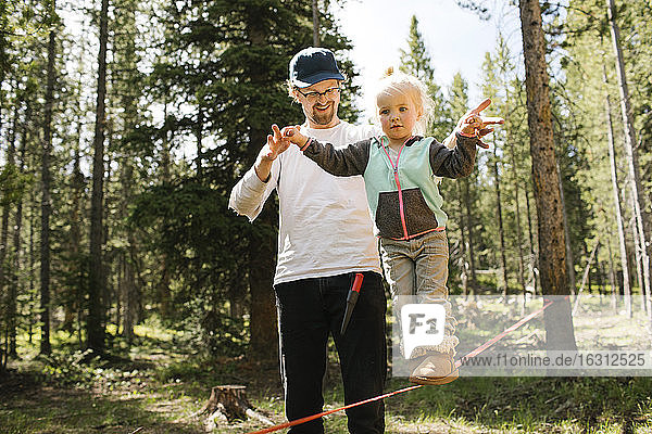Father assisting daughter (2-3) walking on slackline in forest  Wasatch-Cache National Forest