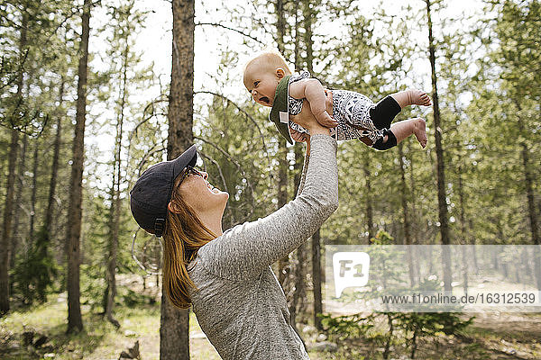 Smiling woman playing with baby son (6-11 months) in forest  Wasatch-Cache National Forest