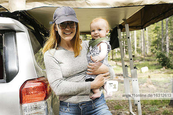 Portrait of smiling woman with baby son (6-11 months) on camping Wasatch-Cache National Forest