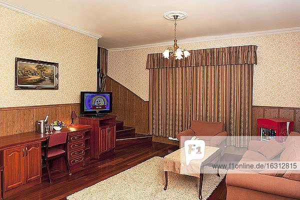 Ein Hotel mit altmodischen Zimmern im Retro-Stil und rustikalen Gegenständen  Sofa und Stühlen und Fernseher.