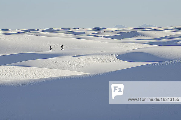 Zwei Personen in einiger Entfernung zu Fuß über weiße Sanddünen.