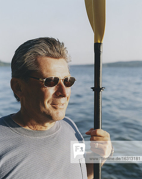 Porträt eines Mannes mittleren Alters mit Seekajakpaddel in der Dämmerung