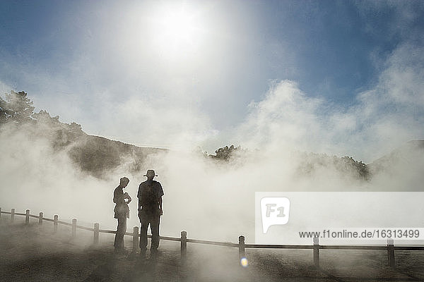 Two people in rising mist at a thermal pool site