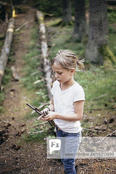 Mädchen hält Stöcke im Wald