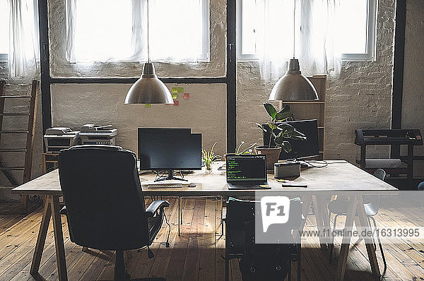 Laptop und Computer am Arbeitsplatz auf einem Tisch angeordnet nach Stühlen