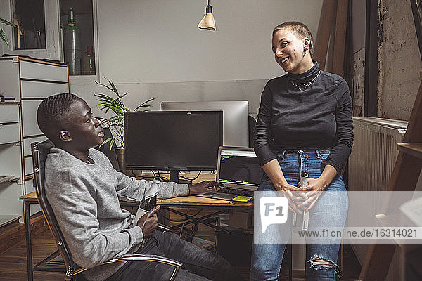 Lächelnde Computerprogrammierer im Gespräch mit Kollegen am Arbeitsplatz