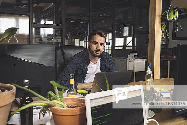 Porträt eines Geschäftsmannes der an einem neuen Arbeitsplatz sitzt
