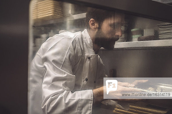 Männlicher Chefkoch backt Pilze in Großküche