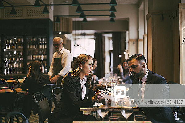 Businesswoman talking to male colleague in restaurant