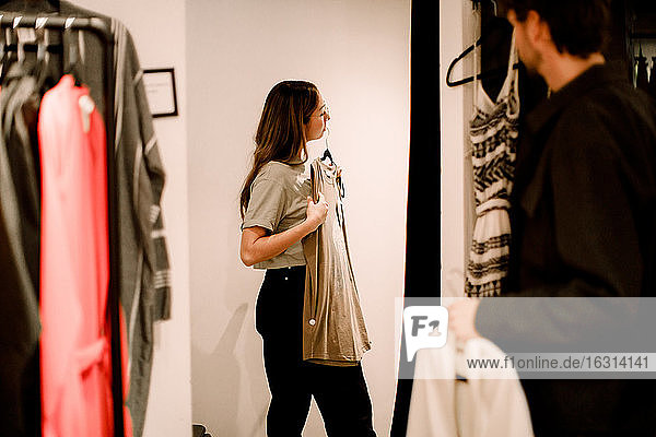 Side view of woman with clothing in retail store