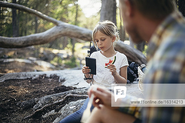 Tochter isst Wassermelone und telefoniert mit ihrem Vater im Wald
