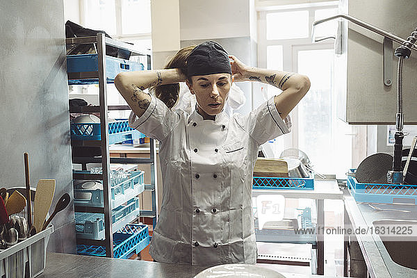 Female chef wearing hat in commercial kitchen