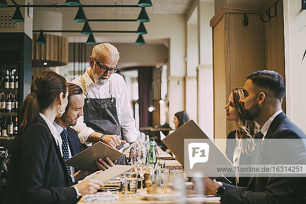 Kellner zeigt Geschäftsleuten im Restaurant die Speisekarte