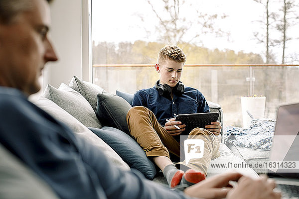 Teenager benutzt digitales Tablet auf Sofa zu Hause