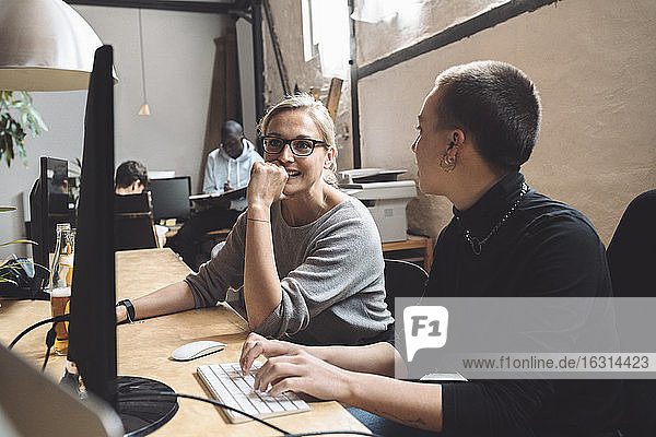 Businesswomen discussing while sitting at workplace