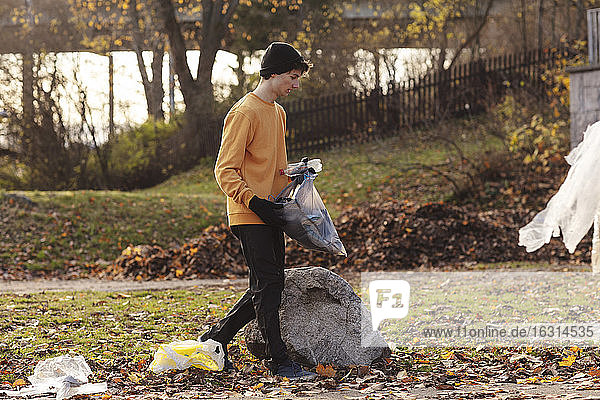 Männlicher Freiwilliger  der beim Spaziergang im Park Müll sammelt