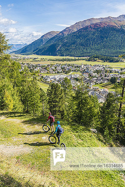 Menschen auf Abfahrtsroller bewundern das Dorf Celerina am Wegesrand  Engadin  Kanton Graubünden  Schweiz  Europa