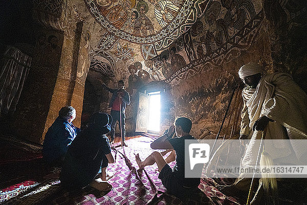 Tourists admiring fresco and paintings inside Abuna Yemata Guh church  Gheralta Mountains  Tigray Region  Ethiopia  Africa