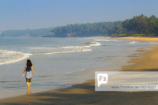 Einsamer Reisender am wunderschönen palmengesäumten Strand von Kizhunna  südlich von Kannur an der Nordküste Keralas  Kizhunna  Kannur  Kerala  Indien  Asien