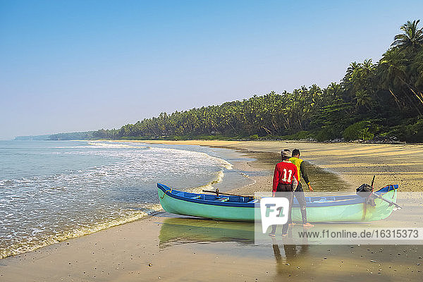 Fischer mit Boot am schönen Strand von Kizhunna  südlich von Kannur an der Nordküste Keralas  Kizhunna  Kannur  Kerala  Indien  Asien