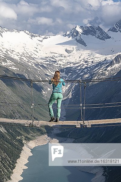 Hiker  woman on suspension bridge at the Olpererhütte  Schlegeis reservoir  Schlegeis reservoir  Zillertal Alps  Schlegeiskees glacier  Zillertal  Tyrol  Austria  Europe