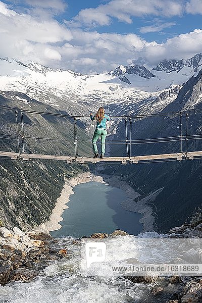 Wanderin  Frau auf Hängebrücke an der Olpererhütte  Schlegeisstausee  Speicher Schlegeis  Zillertaler Alpen  Gletscher Schlegeiskees  Zillertal  Tirol  Österreich  Europa