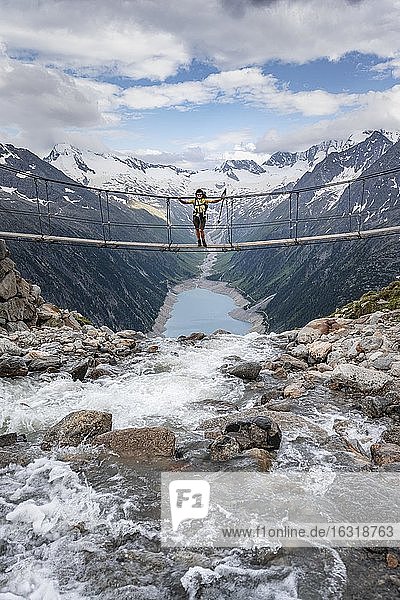 Hiker  woman on suspension bridge at the Olpererhütte  Schlegeis reservoir  Schlegeis reservoir  Zillertal Alps  Schlegeiskees glacier  Zillertal  Tyrol  Austria  Europe